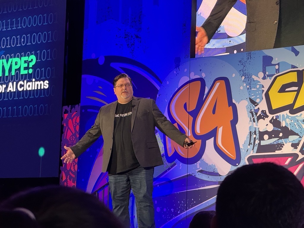 Clint Bodungen presenting on the main stage at S4x25, audience in the foreground